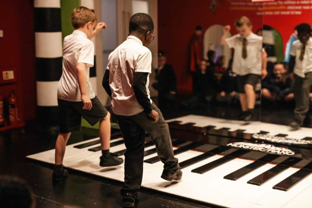 Children in education on the piano in the Discovery Zone at The Beatles Story Museum in Liverpool