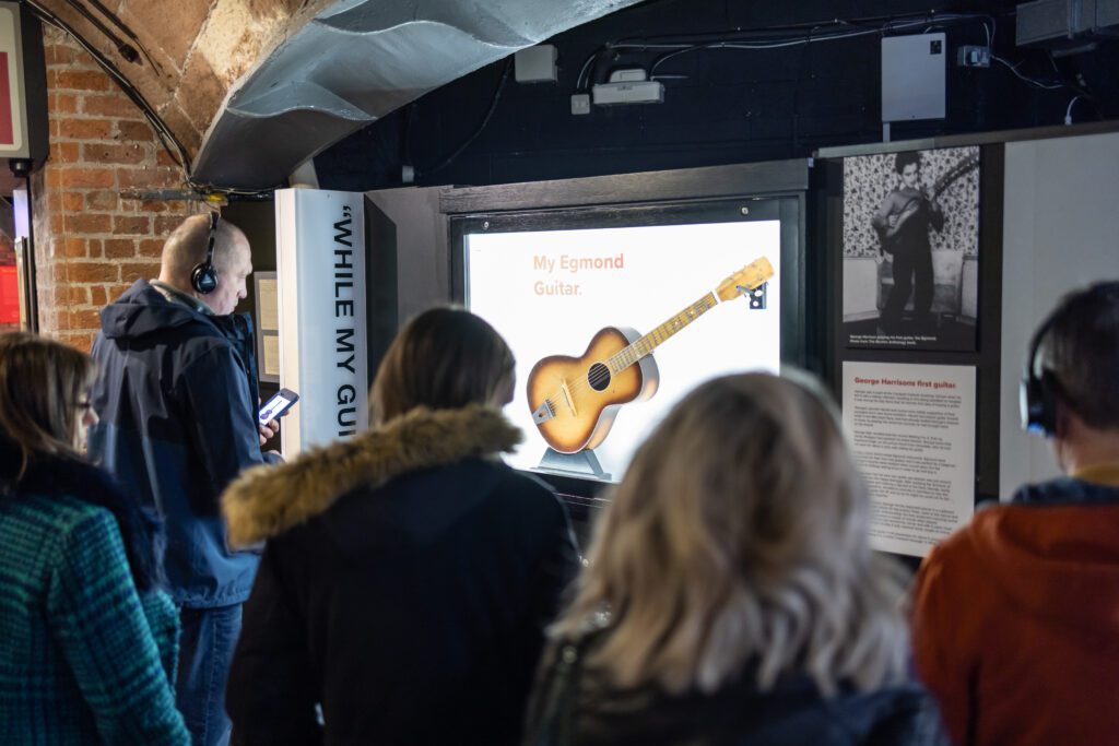 Visitors looking at George Harrison's first guitar memorabilia at The Beatles Story Museum in Liverpool