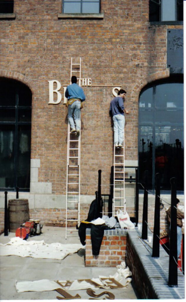 SIGN BEING PUT UP OUTSIDE The Beatles Story when it first opened