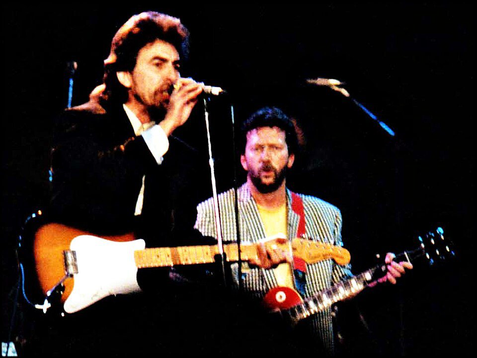 George Harrison and Eric Clapton performing at The Prince's Trust ROck Gala in 1987. Harrison wrote "Here Comes the Sun" in Clapton's garden. Photo by Steve Mathieson, via Wikimedia Commons (CC BY-SA [licence version]).